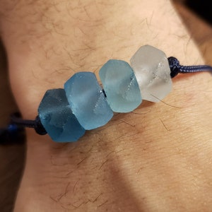 May include: A blue and white glass bead bracelet with a dark blue cord.