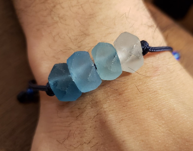 May include: A blue and white glass bead bracelet with a dark blue cord.