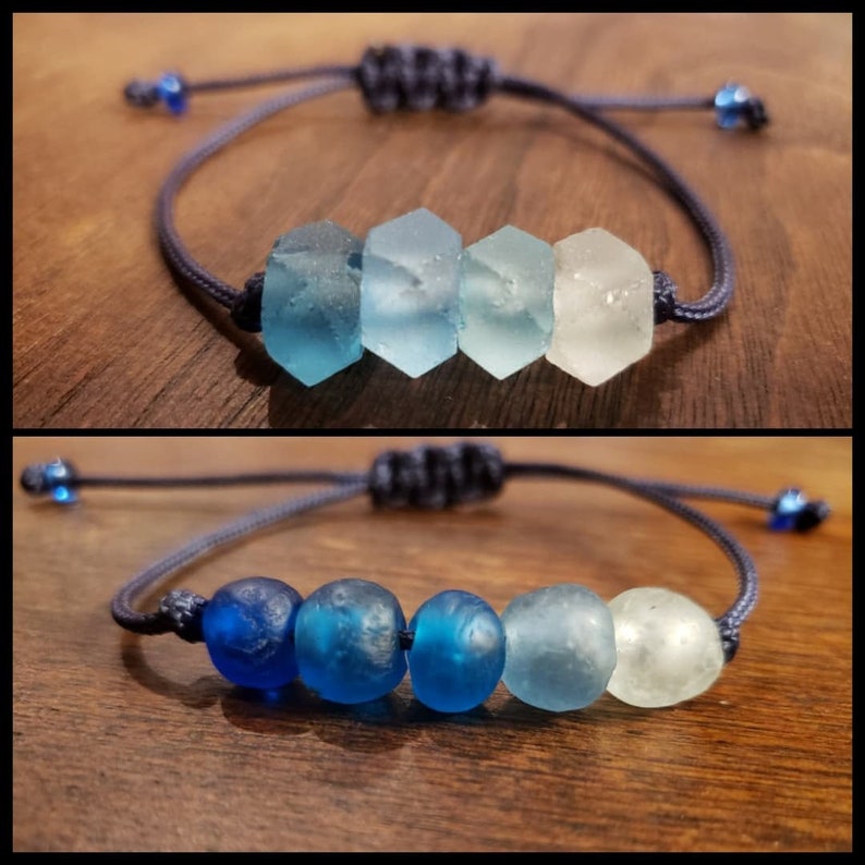 May include: Two bracelets with blue and white glass beads. The top bracelet has four beads, the bottom bracelet has five beads. Both bracelets are made with a dark blue cord.