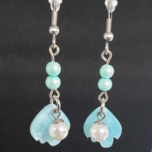 May include: A pair of silver dangle earrings with light blue glass beads and a light blue flower charm with a white pearl at the bottom.