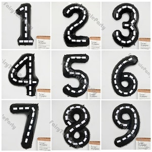 Puede incluir: Nueve globos de números negros y blancos, cada uno con un diseño de carretera blanca, para una fiesta de cumpleaños u otra celebración.