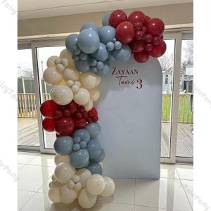 Könnte beinhalten: Ein Ballonbogen aus roten, weißen und blauen Ballons. Der Bogen ist mit den Worten "Zayaan Turns 3" verziert.
