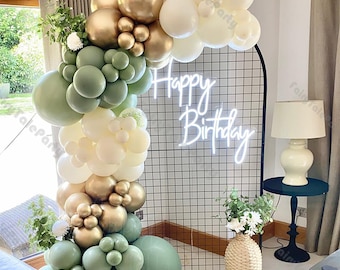 May include: A green, gold, and white balloon arch with a neon sign that says "Happy Birthday".