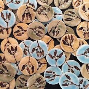 May include: Assortment of ceramic buttons with a floral design. The buttons are in shades of blue, green, and brown.