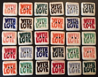 May include: Twenty-four ceramic buttons with the words "With Love" in various colours, including red, blue, green, brown, and white.