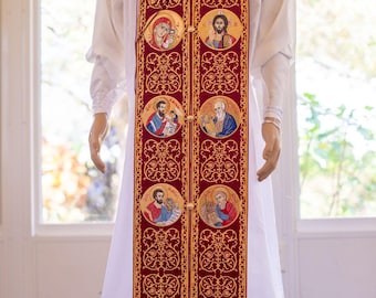 Pode incluir: Uma veste litúrgica bordada em vermelho e dourado com uma variedade de figuras religiosas e desenhos ornamentados.