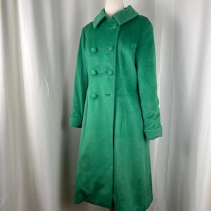 May include: A vibrant green, knee-length double-breasted coat featuring a wide collar, long sleeves with cuffs, and five matching fabric-covered buttons down the front. The coat has a structured silhouette and is displayed on a mannequin.