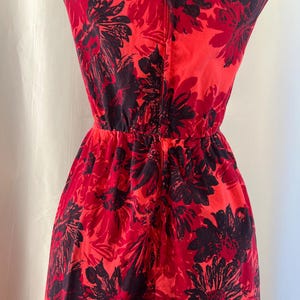 May include: A red dress with a black floral print. The dress features a fitted bodice and a gathered waist. The fabric looks lightweight, ideal for warmer weather. The dress is sleeveless.