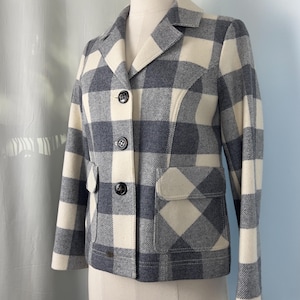 May include: A gray and cream-colored plaid jacket with a classic design. The jacket features a notched collar, three black buttons, and two front pockets. The jacket is displayed on a mannequin.