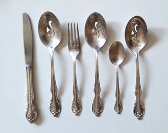 May include: A set of six silver-plated utensils, including a knife, fork, and four spoons. The spoons have decorative cutouts and ornate handles.