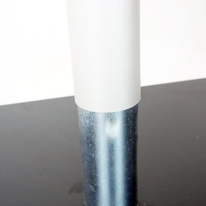 May include: Close-up of a white plastic cover on a silver metal table leg.