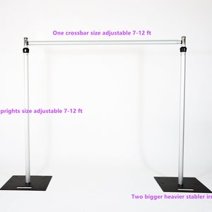 May include: A silver adjustable backdrop stand with two uprights, one crossbar, and two heavy iron bases. The stand is adjustable from 7 to 12 feet in height.