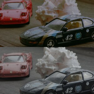 May include: Two toy cars, a red Ferrari and a black BMW, are displayed on a wooden surface. The BMW has a white and blue racing stripe and the number 42 on the side. A white seashell is behind each car.