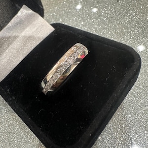 May include: A silver band with a row of small diamonds on each side.