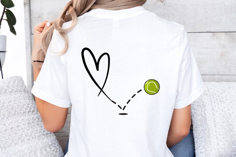May include: White t-shirt with a black hand-drawn heart and a tennis ball with a dashed line connecting the two.