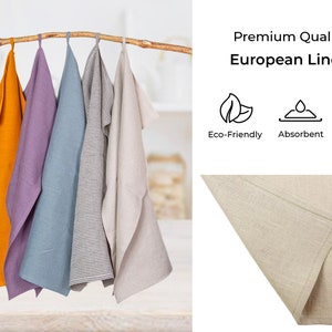 May include: Set of four kitchen towels made from European linen. The towels are in various colors, including orange, purple, blue, and beige. The towels are hanging on a wooden branch. The text "Premium Quality European Linen" is displayed above the towels. Below the text are three icons representing eco-friendly, absorbent, and softer.