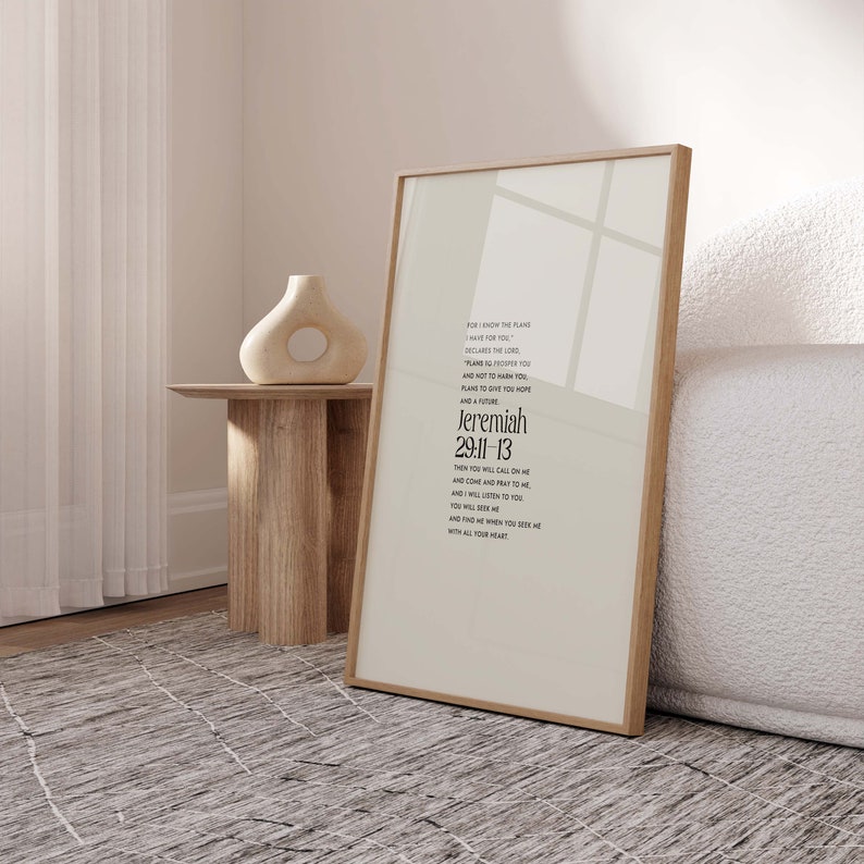 Pu&ograve; includere: Una stampa incorniciata con sfondo beige chiaro e cornice in legno. La stampa presenta il testo "Geremia 29:11-13" in un carattere moderno. Un vaso decorativo e un tavolino in legno sono sullo sfondo.