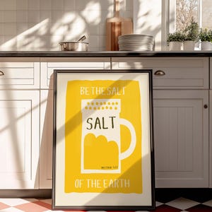 May include: A framed print with a yellow background and a white salt shaker illustration. The text reads "Be the salt", "Salt", "Matthew 5:13", and "Of the earth".