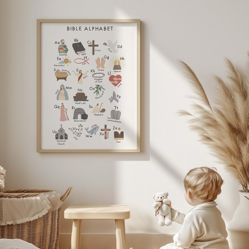 May include: A framed print titled "BIBLE ALPHABET" features colorful illustrations for each letter. The artwork includes religious symbols like a cross, dove, and heart, alongside related words. The print is in a light wood frame.