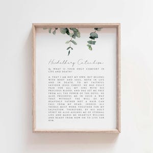 May include: A framed print featuring text from the Heidelberg Catechism, with a light wood frame and eucalyptus sprigs at the top. The text is in a simple, elegant font, and the overall aesthetic is minimalist and modern.