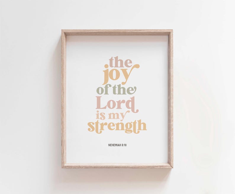 May include: A framed print with the text "the joy of the Lord is my strength" in various pastel colors. The print is in a light wood frame and includes the reference "NEHEMIAH 8:10" at the bottom. The background is white.