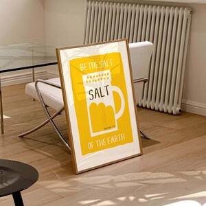 May include: A yellow framed poster with the text "Be the salt" and a white illustration of a salt shaker with the word "SALT" on it. The text "Matthew 5:13" and "of the earth" are also on the poster.