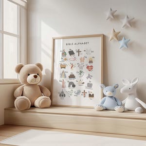 May include: A framed "Bible Alphabet" print with colorful illustrations and text, next to a plush teddy bear, a blue bear, and a white bunny. Decorative star-shaped ornaments hang from the ceiling. The scene is set in a bright room.