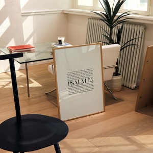 May include: A framed print with a white background and black text. The text is a quote from Psalm 21. The print is sitting on a wooden floor with a black stool in the foreground.