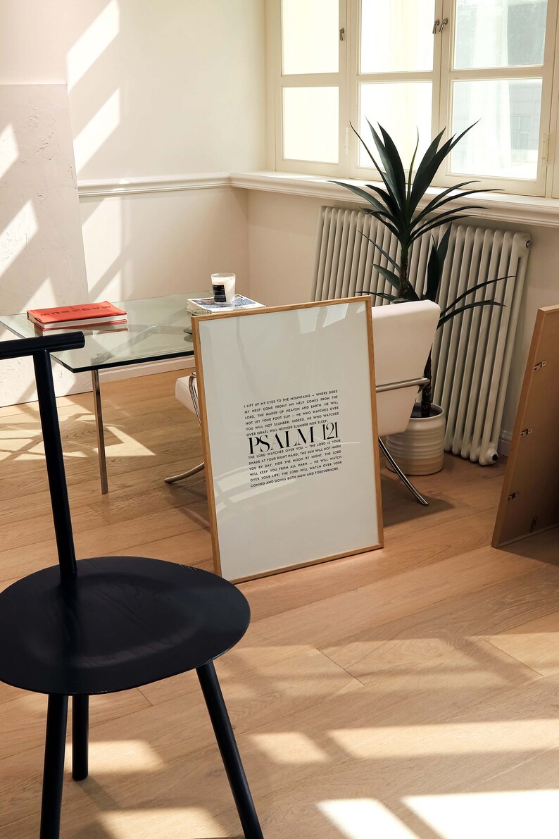 May include: A framed print with a white background and black text. The text is a quote from Psalm 21. The print is sitting on a wooden floor with a black stool in the foreground.