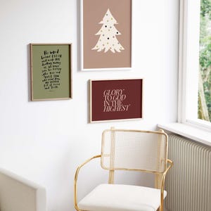 May include: Three framed prints with a Christmas theme. The print on the left has a green background and white text that reads "The word became flesh and made his dwelling among us, but we have seen his glory, glory as of the only Son, who came from the Father, full of grace and truth." The print in the middle has a light brown background and a white silhouette of a Christmas tree with colorful dots. The print on the right has a dark red background and white text that reads "Glory to God in the Highest."