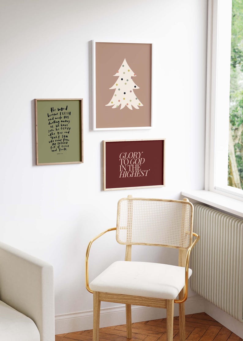 May include: Three framed prints with a Christmas theme. The print on the left has a green background and white text that reads "The word became flesh and made his dwelling among us, but we have seen his glory, glory as of the only Son, who came from the Father, full of grace and truth." The print in the middle has a light brown background and a white silhouette of a Christmas tree with colorful dots. The print on the right has a dark red background and white text that reads "Glory to God in the Highest."
