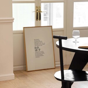 May include: A framed print with a gold frame and a white background. The print features a black and white text quote from the Bible, Ruth 1:16-17, which reads: "Don't urge me to leave you or to turn back from you. Where you go I will go, and where you stay I will stay. Your people will be my people and your God my God."