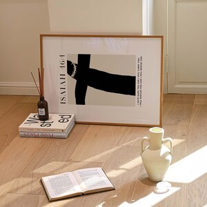May include: A framed black and white print with the text "ISAIAH 46:4 I HAVE MADE YOU AND I WILL CARRY YOU: I WILL SUSTAIN YOU AND I WILL RESCUE YOU."  The print is sitting on a wooden floor with a white vase and three books.