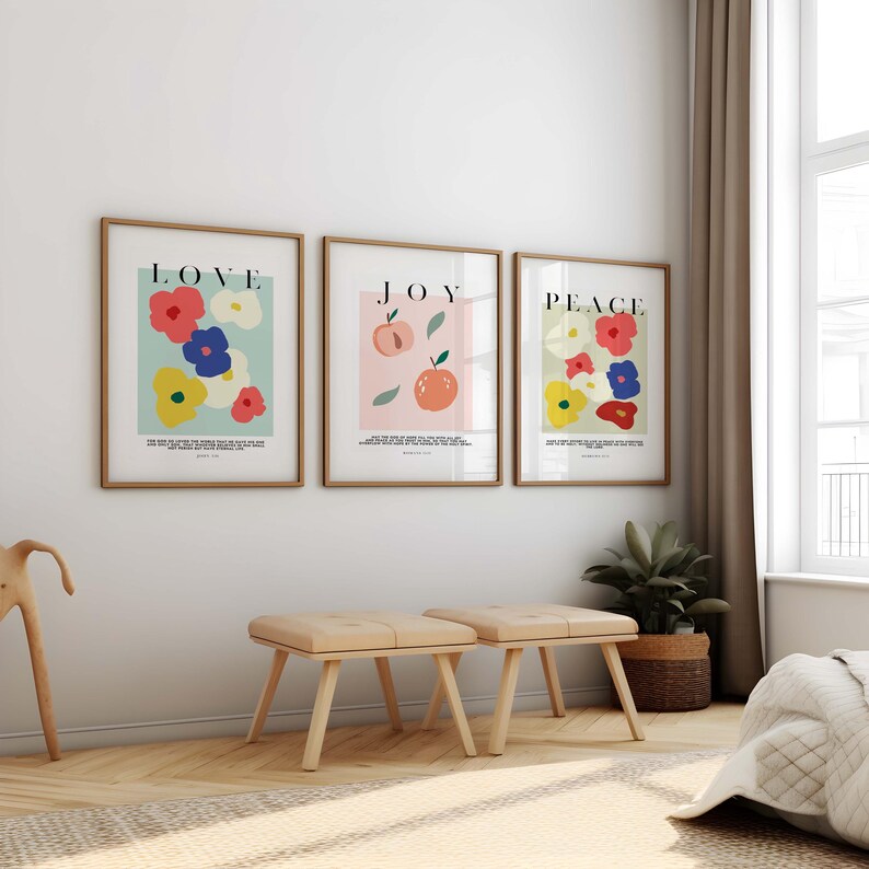 Puede incluir: Tres l&aacute;minas enmarcadas con las palabras "LOVE", "JOY" y "PEACE". La l&aacute;mina "LOVE" presenta flores coloridas, la l&aacute;mina "JOY" tiene melocotones y la l&aacute;mina "PEACE" muestra flores. Dos peque&ntilde;os taburetes de madera est&aacute;n delante.