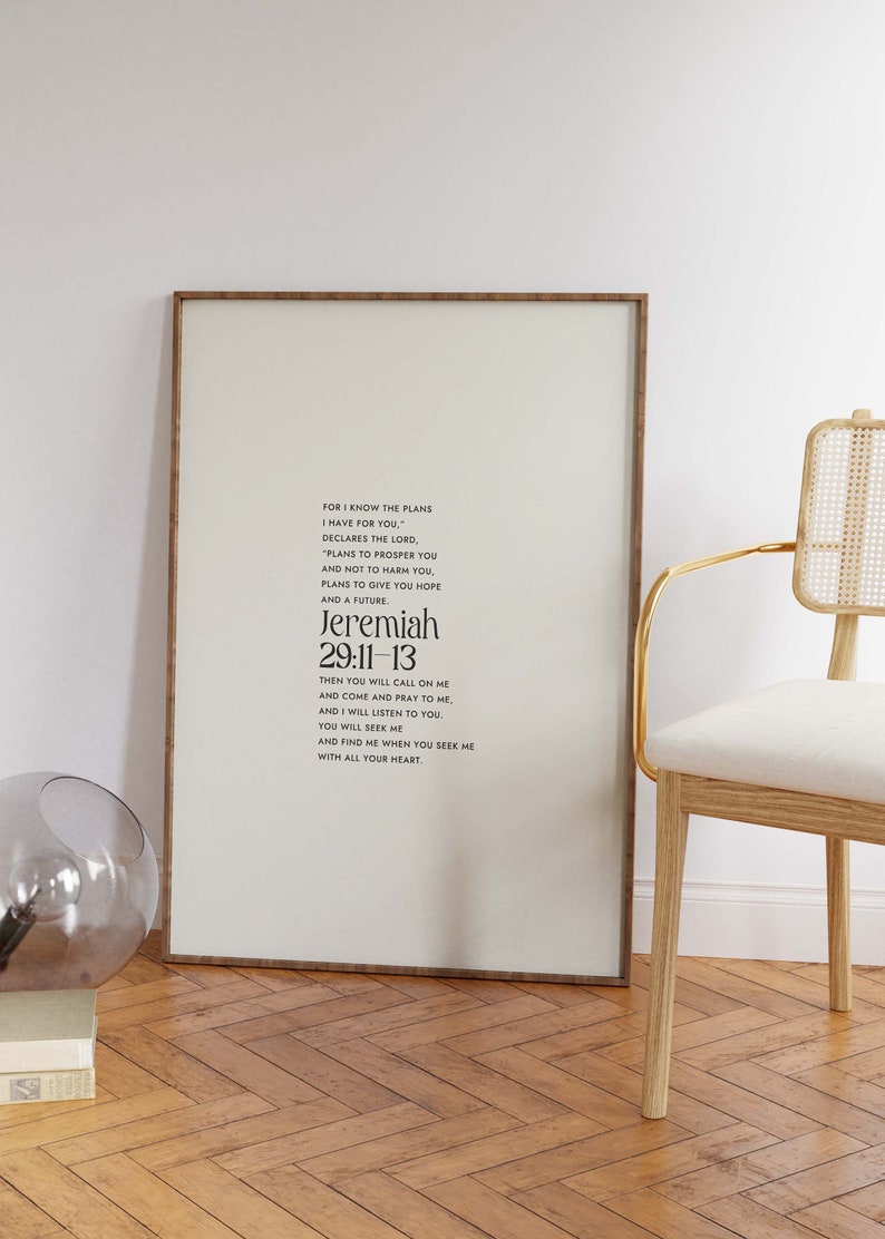 Pu&ograve; includere: Stampa incorniciata con il testo di Geremia 29:11-13 in nero su sfondo crema. La cornice &egrave; in legno scuro. Una sedia moderna con struttura dorata e un globo di vetro sono sullo sfondo. Il pavimento &egrave; in legno.