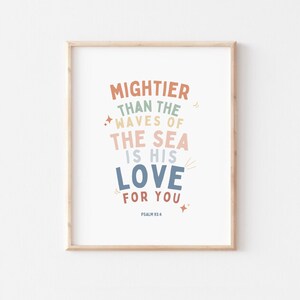 K&ouml;nnte beinhalten: Ein gerahmter Druck mit wei&szlig;em Hintergrund und buntem Text, der "Mightier than the waves of the sea is his love for you." lautet. Der Text ist in einem Regenbogen aus Farben gehalten, darunter Rosa, Blau, Gr&uuml;n und Orange. Am unteren Rand des Drucks steht "Psalm 93:4".