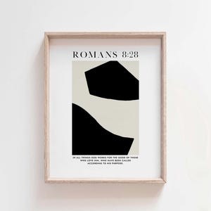 May include: A minimalist art print with black and white abstract shapes. The print features the text "ROMANS 8:28" and the quote "In all things God works for the good of those who love him, who have been called according to his purpose."