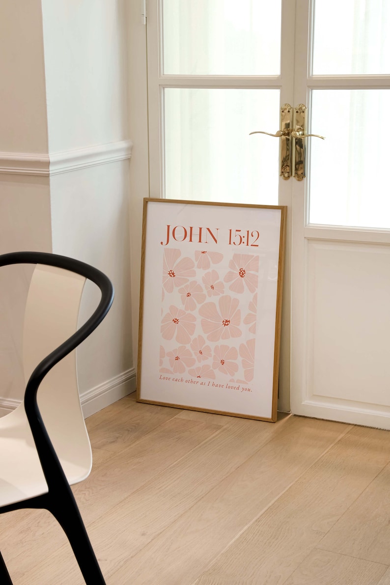 May include: A framed print with a floral design in shades of pink and red. The print features the text "JOHN 15:12" and the quote "Love each other as I have loved you."