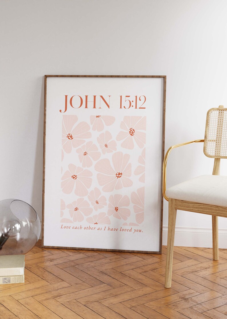May include: A framed print with a floral design and the text "JOHN 15:12" in a brown font. The text "Love each other as I have loved you." is below the floral design.