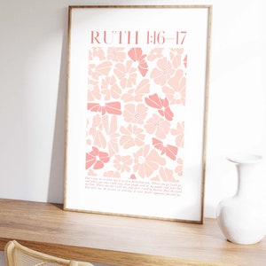 May include: A framed art print featuring a floral design in shades of pink. The print includes the text "RUTH 1:16-17" at the top and a passage below. The artwork is displayed on a wooden surface.
