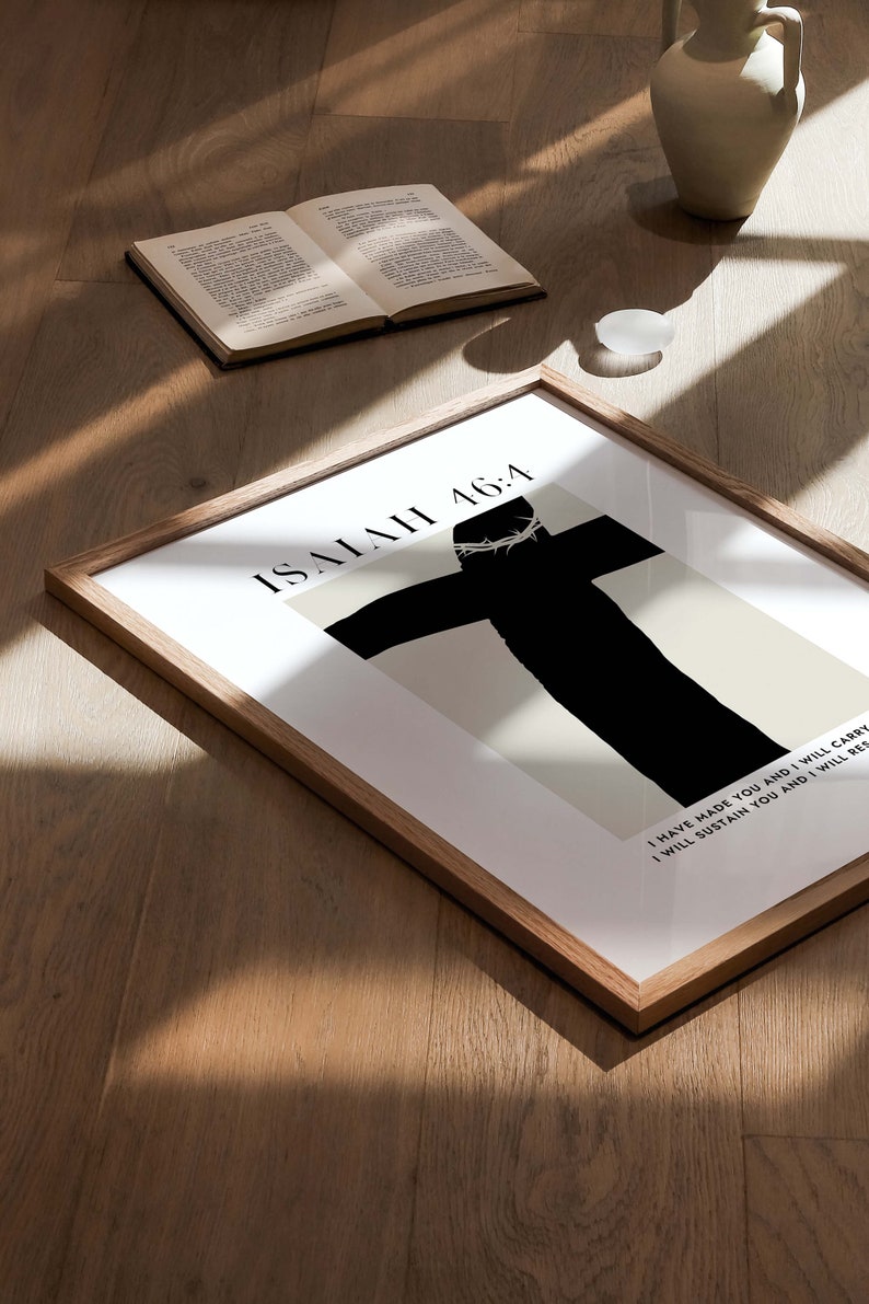 May include: A framed print with a black silhouette of a person on a cross with a crown of thorns. The text "ISAIAH 46:4" is at the top of the print. The text below the image reads "I HAVE MADE YOU AND I WILL CARRY I WILL SUSTAIN YOU AND I WILL RES"