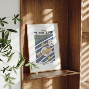 K&ouml;nnte beinhalten: Ein gerahmter Druck mit einem blau-wei&szlig; gestreiften Hintergrund und einer Schale mit Fr&uuml;chten. Der Text "GALATIANS 5:22-23 THE FRUIT OF THE SPIRIT" befindet sich oben auf dem Druck. Der Text unter der Schale mit Fr&uuml;chten lautet: "LOVE, JOY, PEACE, FORBEARANCE, KINDNESS, GOODNESS, FAITHFULNESS, GENTLENESS, AND SELF-CONTROL."