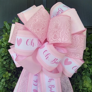 May include: Pink and white ribbon with the text "Oh. Baby!" and hearts. The ribbon has a floral pattern.