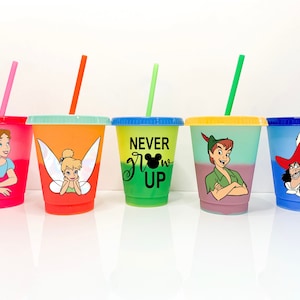 May include: Set of five colorful reusable cups with different Disney characters and designs. The cups have a gradient color effect and feature Tinkerbell, Peter Pan, Captain Hook, Wendy Darling, and a Mickey Mouse logo with the text "Never Grow Up".