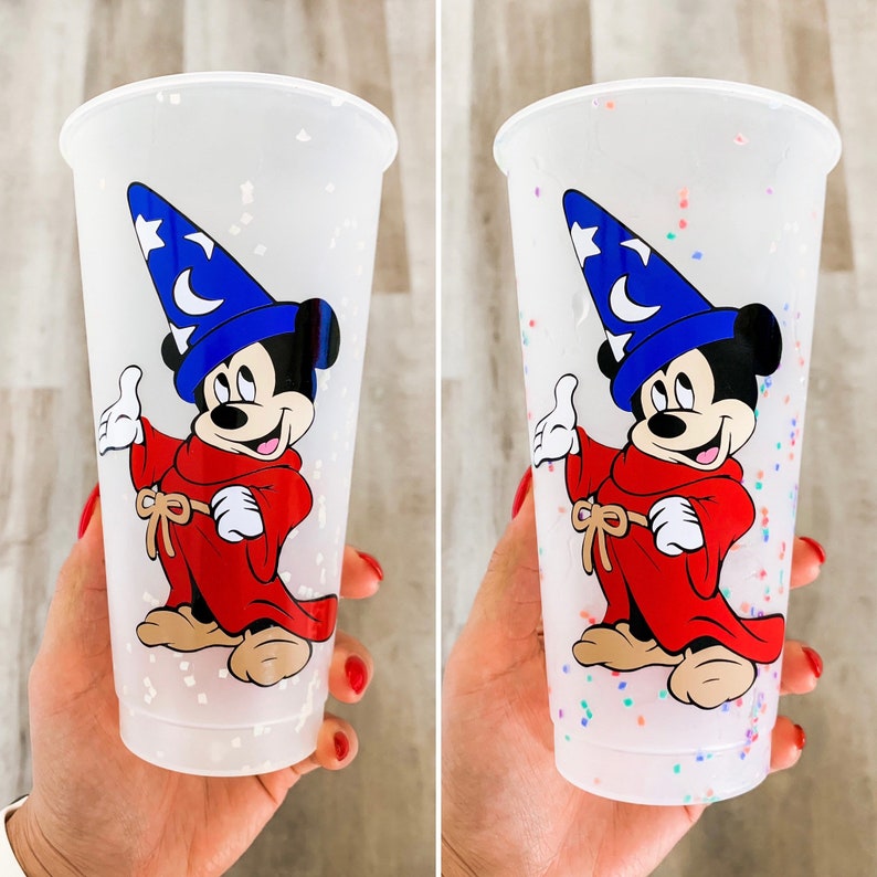 May include: Two clear plastic cups with a white glitter finish. Each cup features a colorful illustration of Mickey Mouse dressed as a sorcerer with a blue hat and red robe.