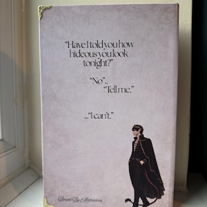 Op de afbeelding: Een rechthoekige print met een citaat: "Have I told you how hideous you look tonight?" met het antwoord "No... Tell me... I can't." Een karakterillustratie staat rechts. De print heeft gouden hoekaccenten en de tekst "Bound By Atamalous".