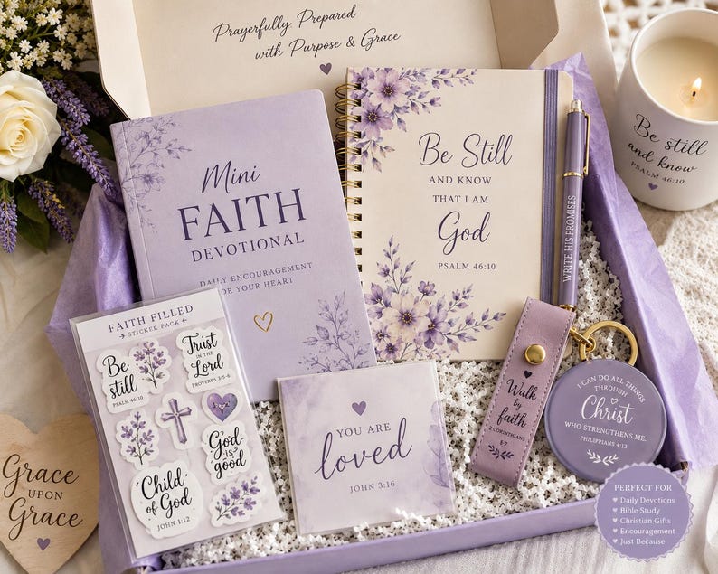 May include: A gift box containing a lavender Mini Faith Devotional book, a spiral-bound journal with floral accents and the text Be Still and Know That I Am God, a matching pen, a sticker pack, a square card, a keychain, and a candle with text.