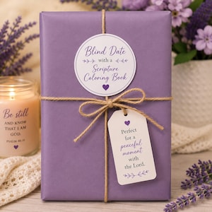 May include: A rectangular object wrapped in solid purple paper, tied with brown twine. A circular white sticker reads Blind Date with a Scripture Coloring Book. A white rectangular tag attached to the twine reads Perfect for a peaceful moment with the Lord.
