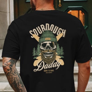 Man wearing black streetwear graphic t shirt 90s aesthetic on the back showing sourdough bread french baguettes with smiling skull. baker shirt sourdough gift streetwear clothing for men. chef baking gifts christmas for sour dough bread baker