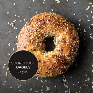 Könnte beinhalten: Nahaufnahme eines Sauerteig-Bagels, bedeckt mit Sesam, Mohn und Gewürzen. Der Bagel ist goldbraun mit einem Loch in der Mitte. Ein schwarzer Kreis in der unteren linken Ecke zeigt "SOURDOUGH BAGELS Digital".